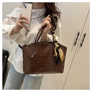 Close-up of dark brown crocodile pattern tote bag with decorative silk scarf