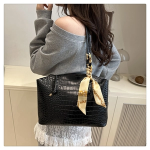 Close-up of black crocodile embossed tote bag with a silk scarf tied on the handle