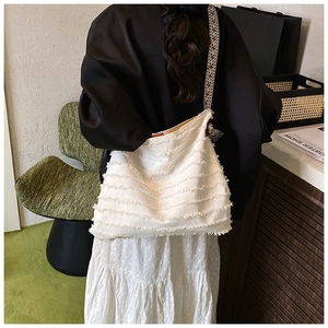 Détail du sac cabas en paille blanc avec texture à franges et bandoulière géométrique