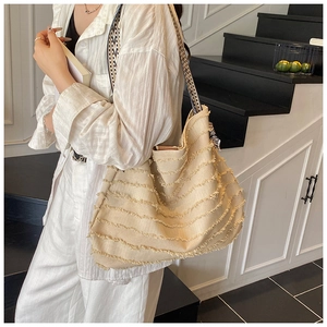 Détail du cabas en toile beige avec bords effilochés et bandoulière en damier