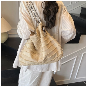 Détail du sac cabas en toile avec texture effilochée et bandoulière géométrique