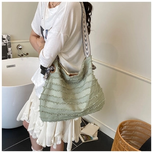 Détail du sac fourre-tout en toile vert clair avec franges et bandoulière géométrique