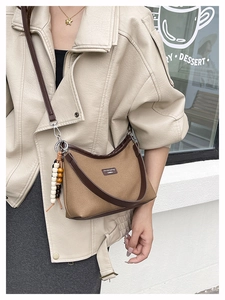 Detail of vintage canvas baguette bag with contrast leather trim and beaded charm accessory