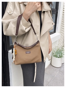 Detail of vintage brown canvas shoulder bag with leather trim and wooden bead tassel
