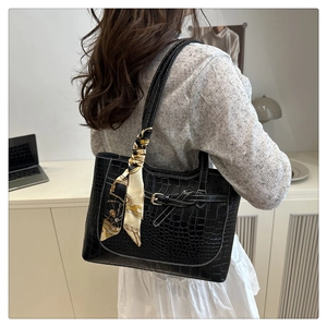 Detail of black crocodile texture tote bag with silk scarf and white contrast stitching