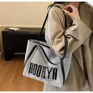 Detail view of canvas tote bag with black leather handles and HOORYA logo print