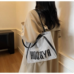 Detail of canvas tote bag with black leather straps and HOOAYA logo lettering