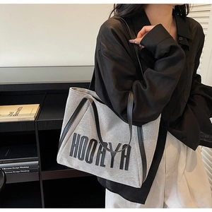 Detail of the large canvas tote bag with black leather straps and HOORYA lettering