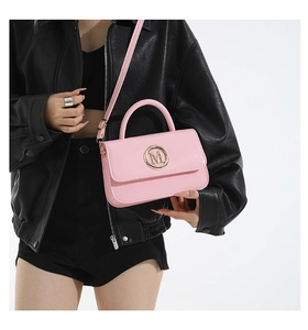 Detail of pink patent leather handbag featuring golden M logo and sleek glossy finish