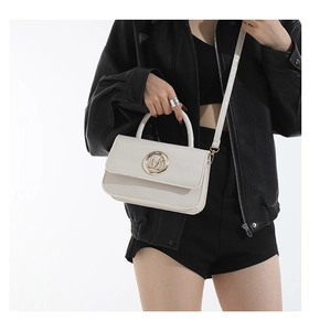 Borsa a tracolla in pelle beige alla moda con logo M dorato indossata da una modella