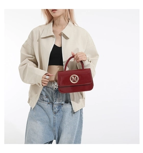 Detail of glossy wine red patent leather mini bag featuring a gold M logo buckle accent