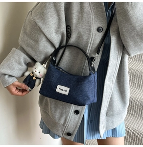 Denim patchwork crossbody bag with plush bear charm shown on model in a modern indoor setting