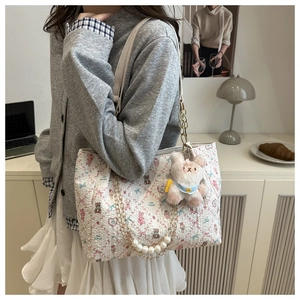 Détail du cabas blanc à motifs d'ours avec chaîne de perles et breloque peluche