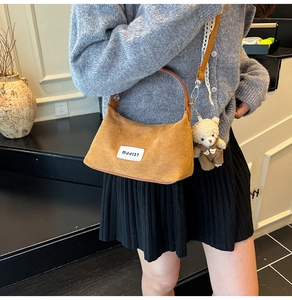 Detailed view of the brown suede handbag featuring a teddy bear charm and MJJ137 leather tag