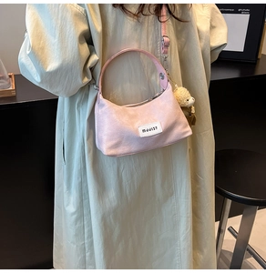Pink suede dumpling bag with MDDJ37 logo shown on beige coat with plush bear charm