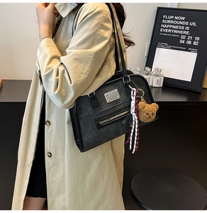Gros plan sur un sac cabas rétro noir mat avec détails argentés et breloque ours