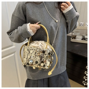 Close-up of champagne gold sequin bucket bag with drawstring and ring handle