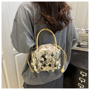 Close-up of shimmering gold and silver sequin bucket bag with metallic drawstring lining