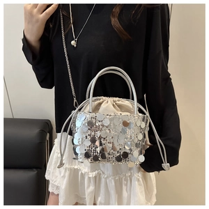 Detailed view of silver sequin bucket bag with drawstring closure and chain strap
