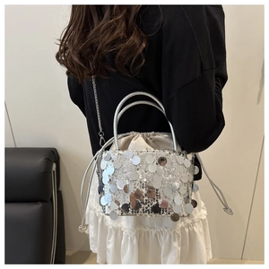 Macro shot of silver sequin bucket bag featuring drawstring closure and metallic handle