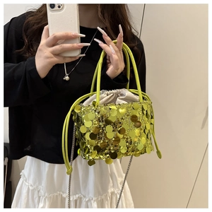 Detail of bright green sequin bucket bag with drawstring closure and metal chain strap