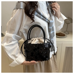 Detail of black sequin bucket bag with contrast white satin drawstring liner pouch