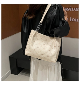 Détail du sac cabas crème présentant un motif texturé et un imprimé de marque élégant