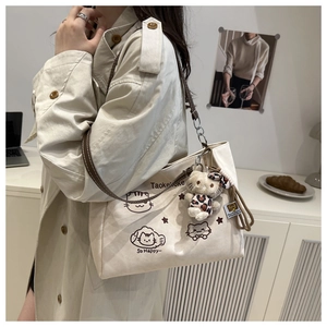 Close-up of canvas tote with cute cat prints and brown leather handles on shoulder