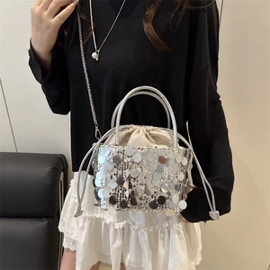 Silver sequin drawstring bucket bag with a metal chain strap shown on a model