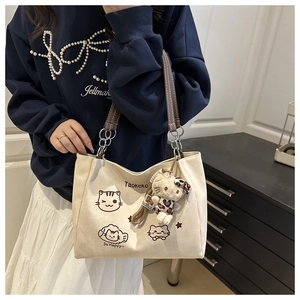 Detail of canvas tote bag featuring cartoon cat prints and leopard plush charm