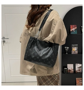 Vue latérale d'un sac cabas noir avec chaîne argentée porté par un mannequin