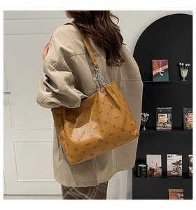 Detail of caramel leather tote bag featuring cartoon rabbit logo and silver metal chain strap