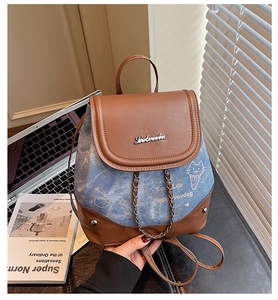 Detail of leather and denim patchwork backpack with cat prints and metal logo
