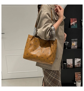 Détail d'un sac cabas marron à motifs avec bandoulière en chaîne porté par un mannequin