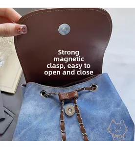 Detail of blue denim backpack showing strong magnetic buckle and metal chain drawstring