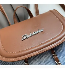 Close-up of brown leather mini backpack featuring silver metal logo and fine stitching