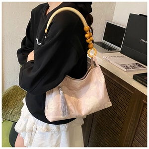Détail du sac à fleurs avec perles en bois, anse tressée et détails à franges