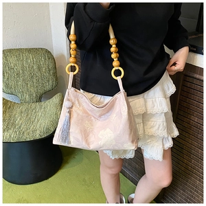 Détail du sac à main fleuri rose avec poignée en perles de bois et gland décoratif
