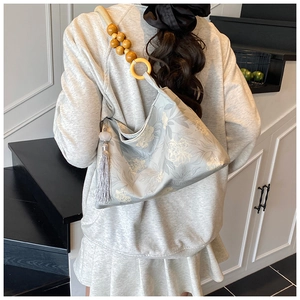 Détail du sac seau en jacquard floral avec bandoulière en perles de bois naturelles