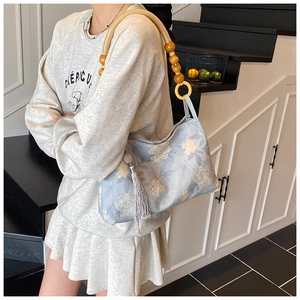 Détail du sac seau bleu clair avec motifs floraux et bandoulière en perles de bois