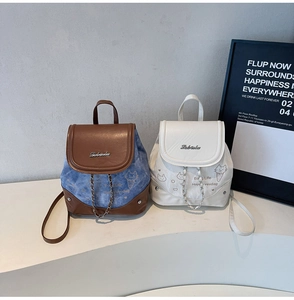 Detail of color-block mini backpacks with cartoon cat print and elegant metal chain charms