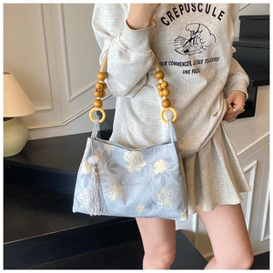 Détail du sac cabas floral bleu clair avec poignée en perles de bois et pompon