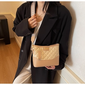 Close-up of apricot quilted chain bag featuring FASHION text on modern office blazer