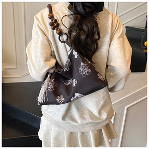 Détail du sac bandoulière en toile noire avec motif floral et bandoulière en bois