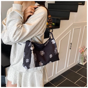 Détail du sac seau floral avec bandoulière en perles de bois et gland argenté
