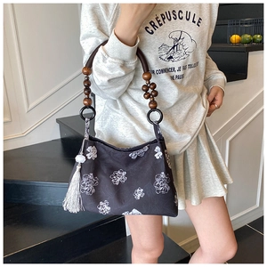 Détail du sac à fleurs rétro avec poignée en perles de bois et pompon en soie blanc