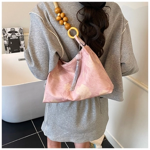 Détail du sac seau floral rose avec bandoulière en perles de bois et pompon gris