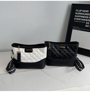 Close-up of quilted fashion crossbody bags with wide arrow straps and chic letter tags