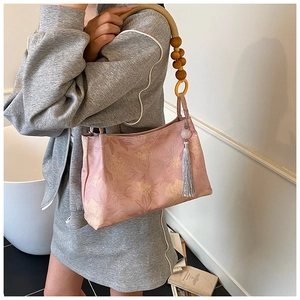 Détail de la poignée en perles de bois et gland de soie sur le sac seau fleuri rose