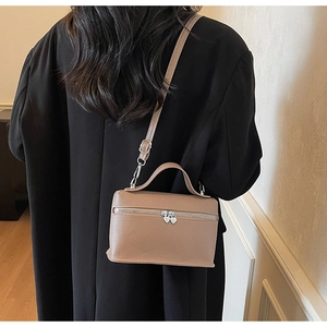 Rear view of khaki mini box bag with heart zippers on a model in a black coat